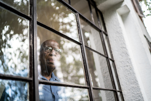 Older man facing window by himself - Shutterstock image